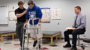 A college student using a walker with assistance