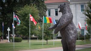 The bear statue with flags of different countries on campus.