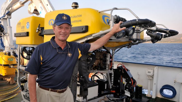 Dr. Robert Ballard stands next to a yellow sea exploration machine