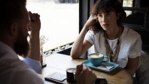 A man and woman having a conversation at a cafe.