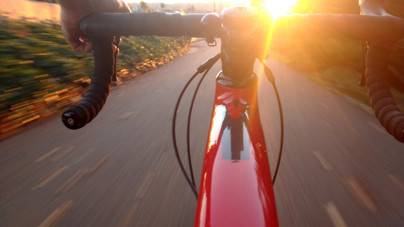A view of bike handlebars facing a sunset