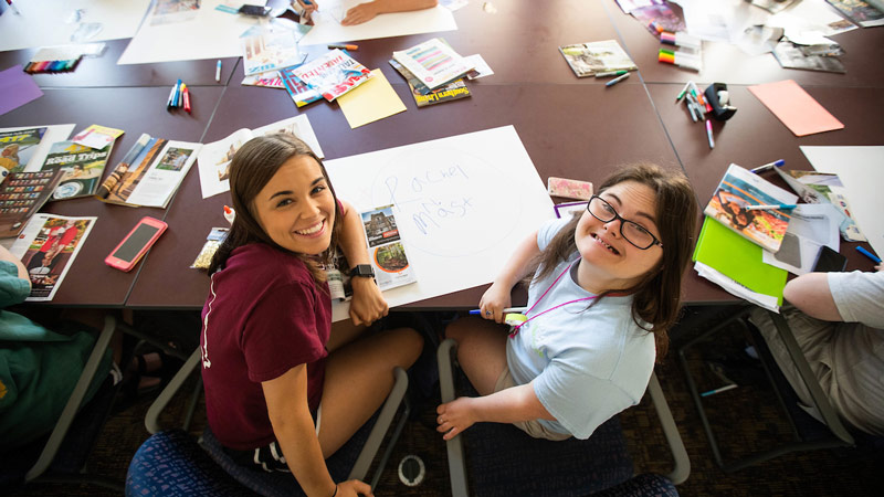 A mentor and Bear Power student sit at a maroon table to work on a project