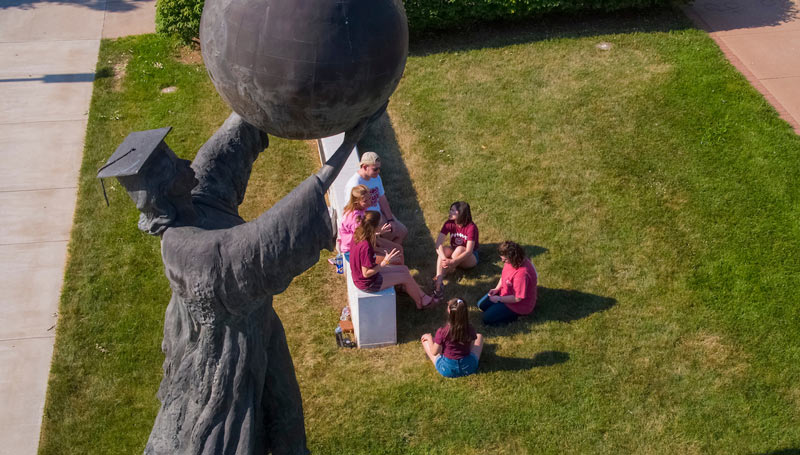 The Citizen Scholar statue towers over a group of students