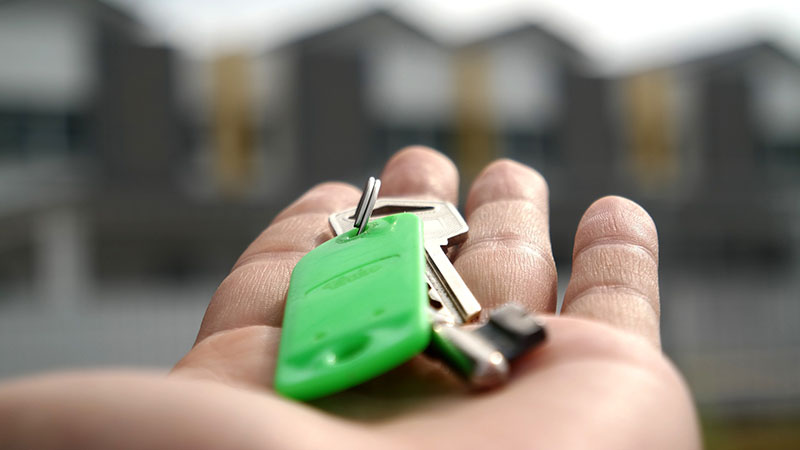 A hand holding keys to a house.