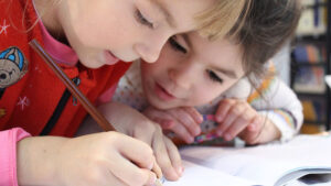 Two young children practice writing and drawing.