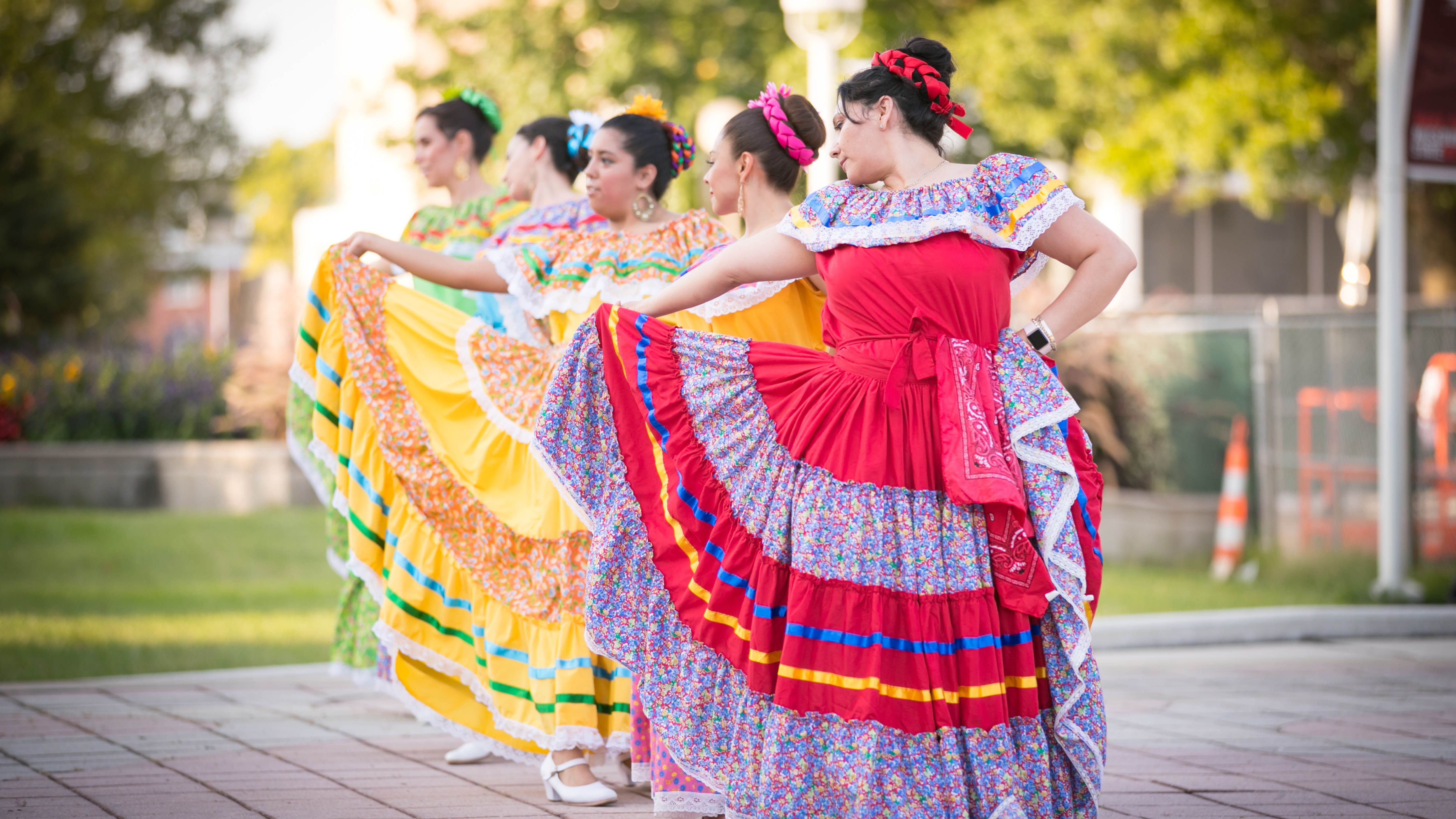 Five women is colorful dresses dancing