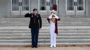 A veteran salutes next to a member of the Pride Band as they perform Taps outside McDonald Arena.