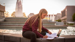 Woman does schoolwork by fountain