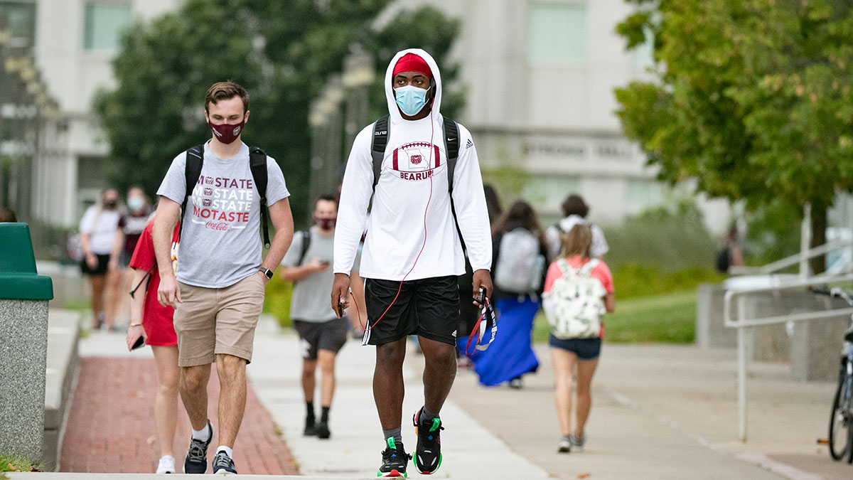 Masked students walk between Strong and Glass halls.
