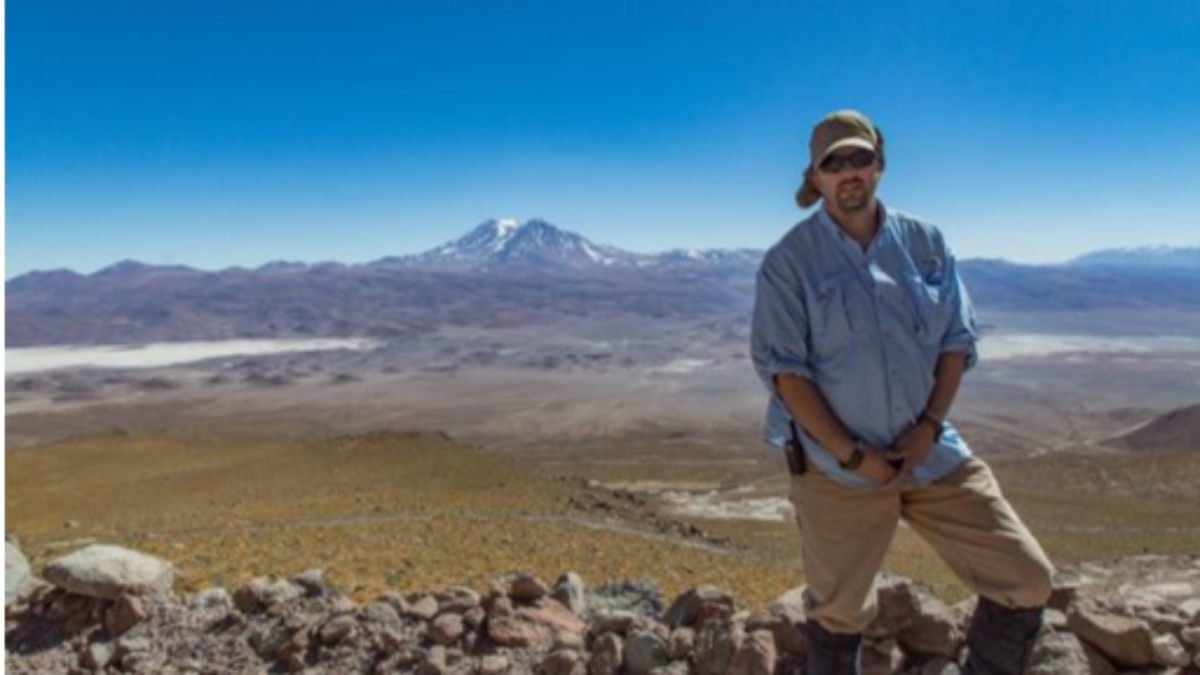 Dr. Michelfelder on a debris avalanche at Ollagüe volcano overlooking Aucanquilcha Volcano.