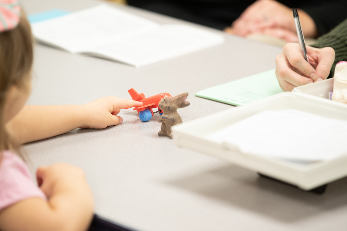 Preschool student points to toy plane.