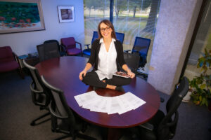 Dr. Carrisa Hoelscher sits on conference table surrounded by her research articles.