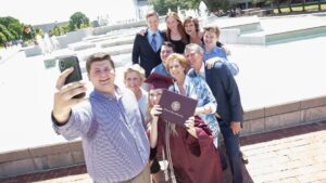A family poses for a photo with their Missouri State graduate at the John Q. Hammons Fountain.