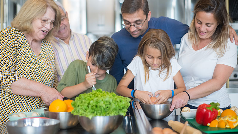 A family cooks together in the kitchen.