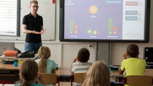 A teacher teaching a group of elementary school kids in the classroom.