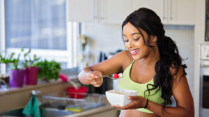 A woman holding a bowl and eating breakfast.