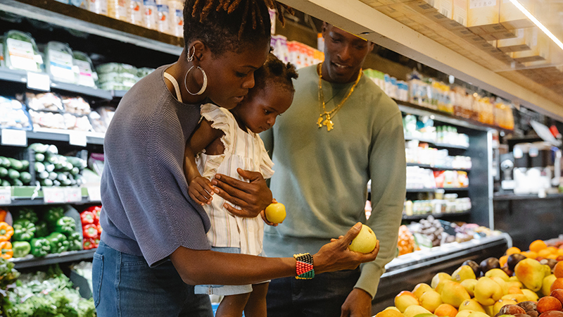A family looking at fruits in a grocery store.