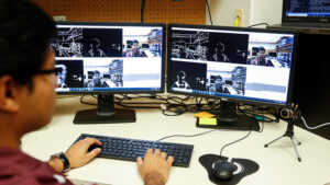 A man typing on a keyboard while looking at two monitors.