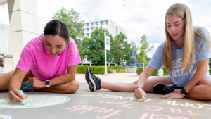 Two Missouri State female students draw on campus with chalk