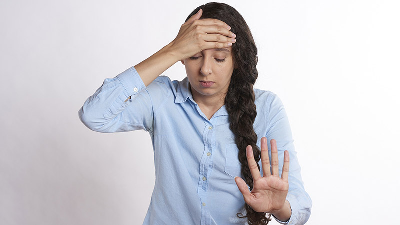 A woman in discomfort with her hand on her forehead.