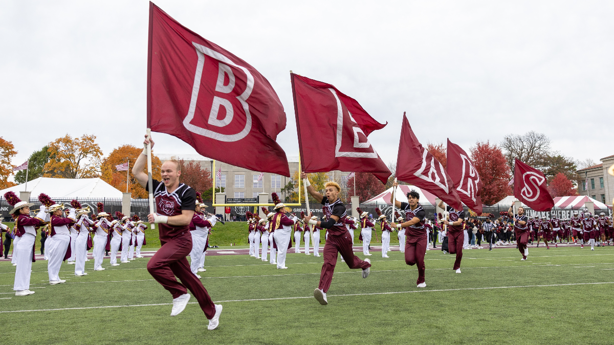 MSU cheerleaders carrying flags that spell BEARS across the football field