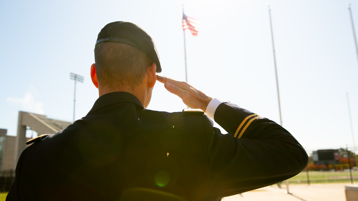 Man in uniform salutes American flag
