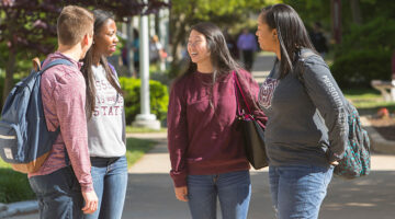 Four students having a conversation on campus.