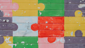 Multi-colored puzzel pieces painted on a brick wall.