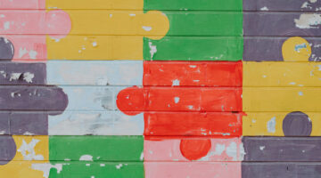 Multi-colored puzzel pieces painted on a brick wall.
