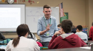 A student teacher stands at the front of a high school clasroom
