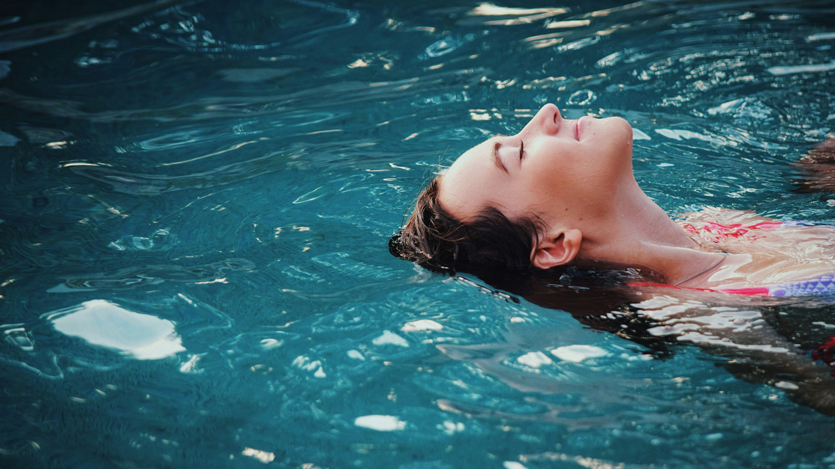 Person floating peacefully in a swimming pool.