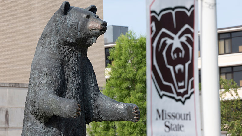 The Plaster Student Union Bear statue and Bear head logo banner.