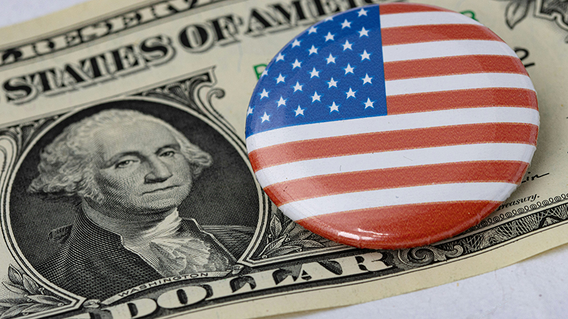 A round badge of the American flag on a $1 bill.