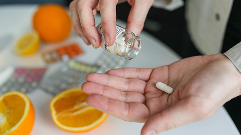 A person holds a vitamin c supplement.
