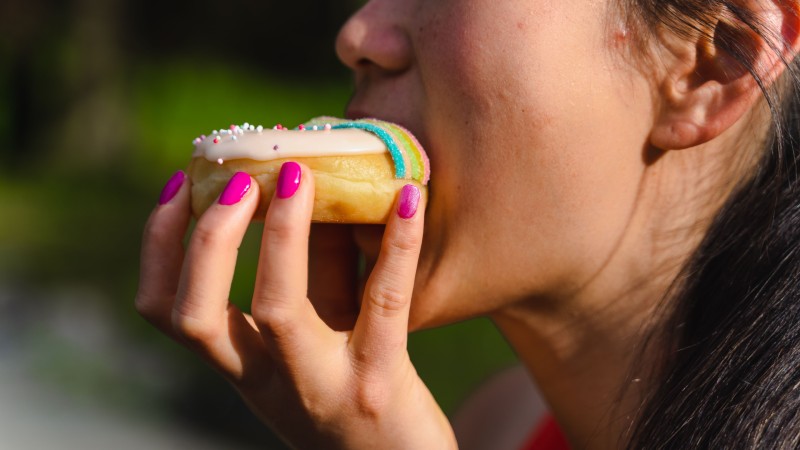 A woman biting on a donut.