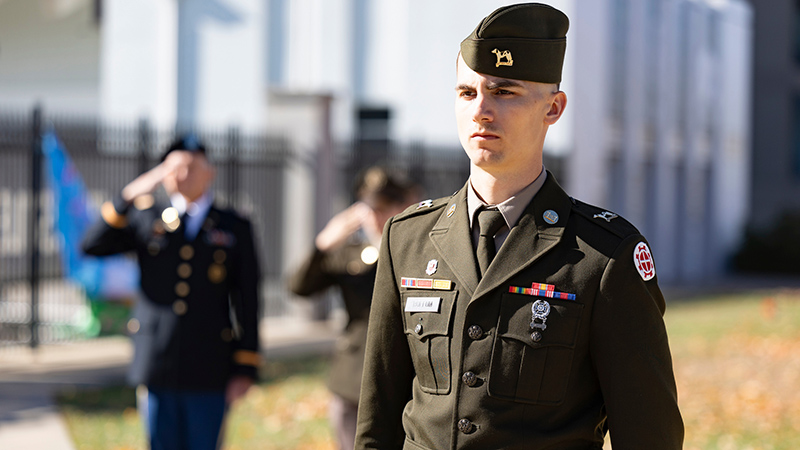 Three individuals in military uniforms at the 2025 Taps ceremony on campus.